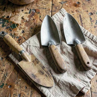Atmospheric overhead of a worn worktop with three garden trowels in graduated si