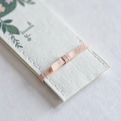 Macro of a small chapbook insert with sewn-in ribbon bookmark