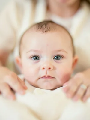 Baby's face in focus, parent's arms blurred