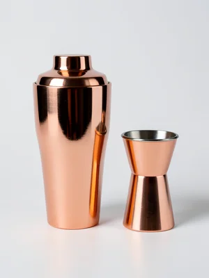 A copper cocktail shaker, polished to a mirror finish, reflecting the studio lig