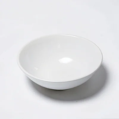 An empty white ceramic bowl on white surface, subtle shadow the only indication 