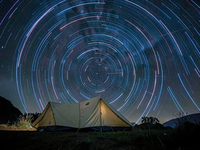 Single tent under star trails, two hours of earth rotation creating perfect circ