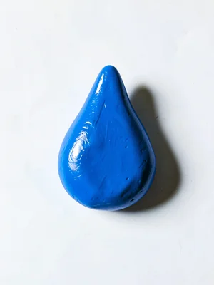 Glossy chunky clay raindrop in primary blue with stubby pointed top and oversize