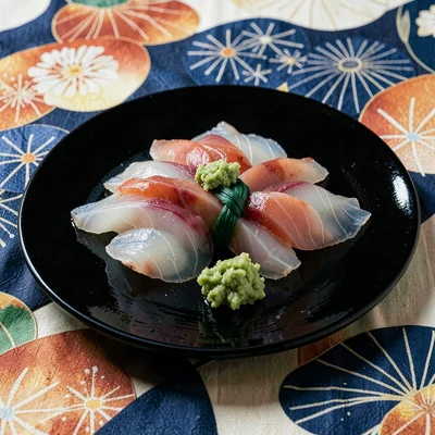 Through the textile eye of Kyoto, woven and dyed, Sashimi arranged on a black la