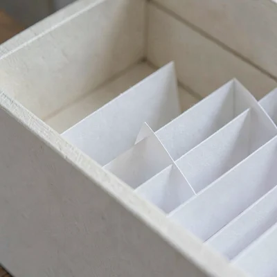 Macro of folded paper dividers fitted into a drawer compartment, soft fiber grai