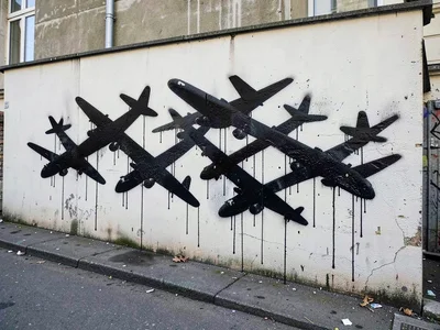 Group of birds morphing into aeroplanes, stencilled across a long render wall, d