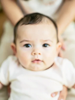 Baby's face in focus, parent's arms blurred