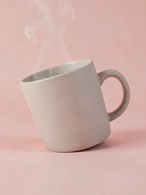 Curvy ceramic mug with matte glaze captured at slight tilt on a blush pink seaml