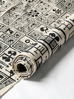 Bolt of finished Adinkra cloth rolled — repeating symbol pattern visible on end 