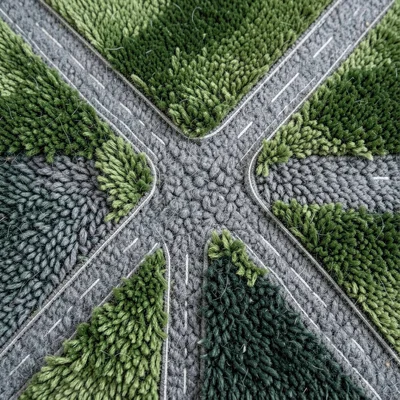 A highway interchange from above, the roads as gray berber carpet against green 