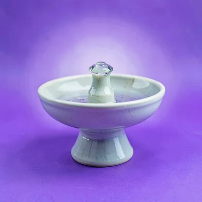 single ceramic pet-water-fountain top straight-on against a saturated lavender b