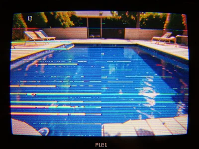 Paused home video of swimming pool, blue water fragmented by tracking errors int