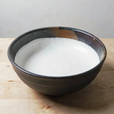 A large mixing bowl with a poured white slip interior and dark stoneware exterio