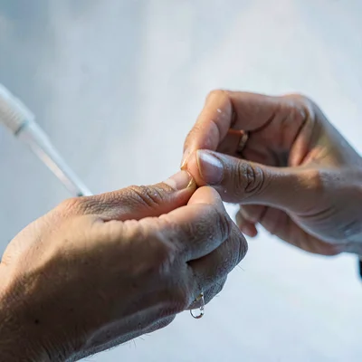Editorial close-up of a model's hands rubbing oil between fingertips, soft cool