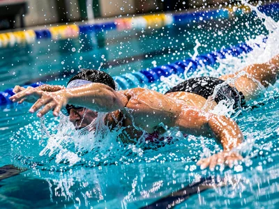 Swimmer doing butterfly stroke in a pool, water droplets frozen mid-splash