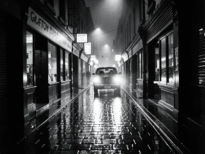 Grafton Street after midnight, wet flagstones reflecting shop signs, a single ta