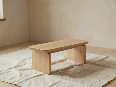 One small low wooden bench of pale oak with rounded apron centered on cream line