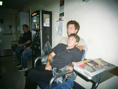 Hospital waiting room at 3am, person in plastic chair with vending machine coffe