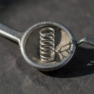 Macro lightbox study of a julep strainer head, coiled spring catching directiona