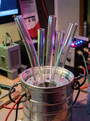 A cluster of glass tube offcuts in varying diameters standing upright in a metal