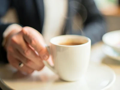 Hand reaching for coffee cup, background dissolved