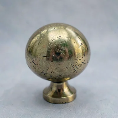 Tight texture study of brass tap handle scuffs with a single key light