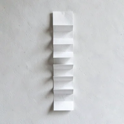 Vertical accordion of folded press-clip rectangles climbing the frame, raking sh