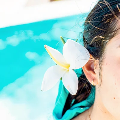 Expansive turquoise negative space, bleached whites, A single tiare flower behin