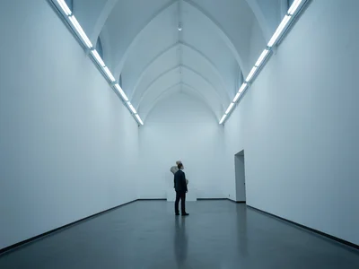 Museum interior with vast white walls, single sculpture, person standing for sca