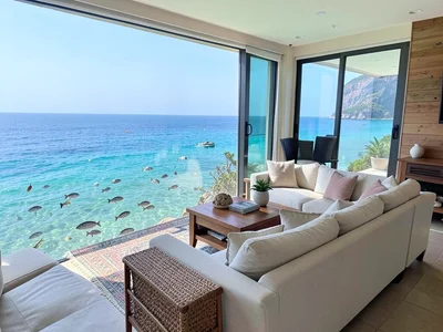 Fully furnished living room at bottom of clear ocean, fish swimming past couch