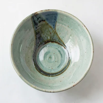 Overhead view of a wide celadon bowl with glaze pooling deep at the foot