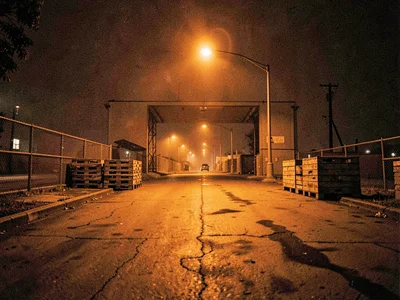 Loading dock with orange industrial lighting, empty pallets, night shift absence