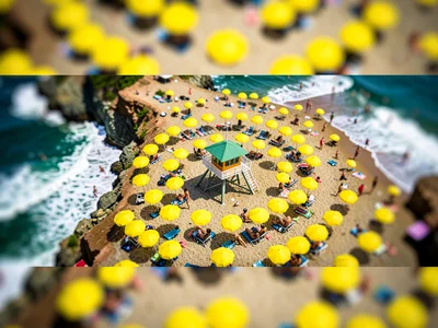 Above a coastal cliff tilt-shift photograph of a packed beach, saturated lemon u