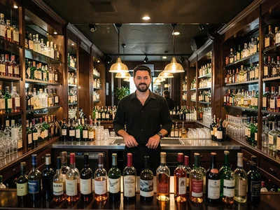 Bar interior, bottles in perfect rows, mirror reflection doubling everything, ce