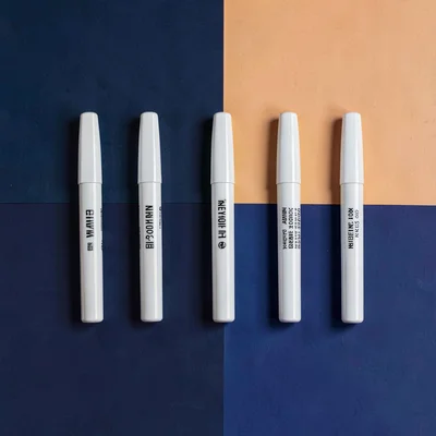 Catalog shot of seven markers lined on a deep navy color-block, crisp wraparound