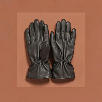 Centered catalog hero of a pair of leather gloves on a saturated terracotta colo