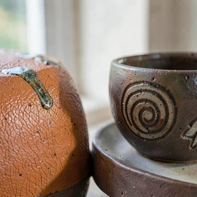 Salt-fired stoneware shoulder, orange-peel skin marching past a deep thumbprint