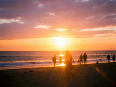 Beach sunset with silhouettes of people, warm orange and purple sky