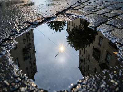 Puddle on asphalt reflecting single streetlight, point source creating starburst