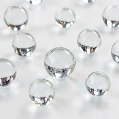 Glass marbles scattered on white surface, spherical refraction, childhood glass