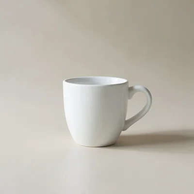Minimalist photography of a single white coffee cup on a clean matte surface, soft natural window light, subtle shadow, 