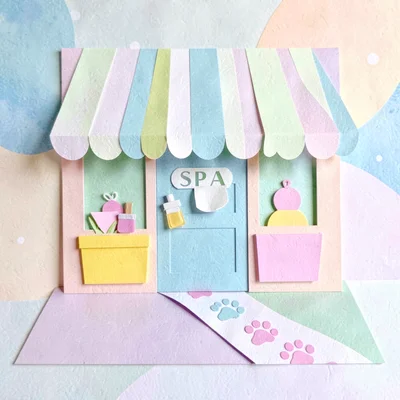 Playful cut-paper scene of a spa storefront with a striped awning and paw-print 