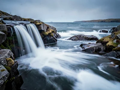 Waterfall blur meeting ocean blur in rocky cove