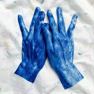 Two hands overlapping pressed onto cotton fabric — cyanotype blue silhouette, co