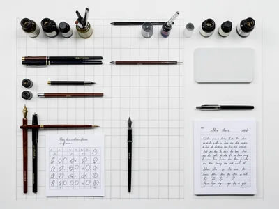 A calligrapher's desk: nibs, ink bottles, pen holders, blotter, practice sheets,