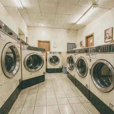 Grainy digital illustration, laundromat with spinning machines , film grain text