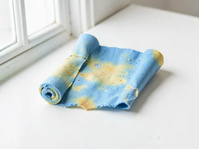 Yellowing faded-blue scroll of paper with thumb-pressed creases along its roll a