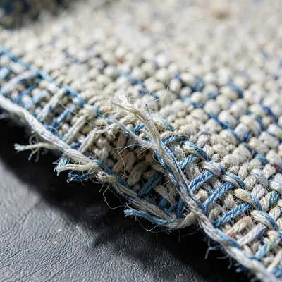 Mineral-cut macro of a worn handwoven textile edge with frayed threads, deep rak