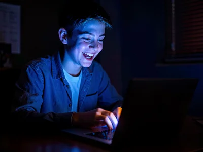 Teenager receiving college acceptance on laptop, joy in screen-lit face, the lif