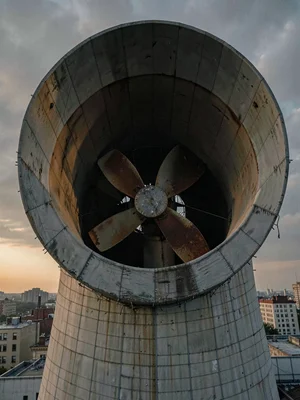 The wide circular maw of a cooling tower fan opens skyward, catching faint amber